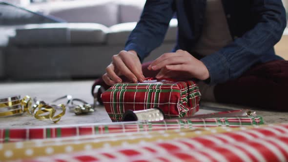 Mid section of woman wrapping Christmas presents at home