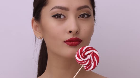 Fashion Portrait of Asian Woman with Lollipop in Studio
