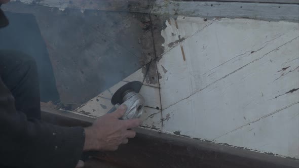 Cutting out rotten mahogany planking with angle grinder on eighty year old wooden boat. MEDIUM SHOT