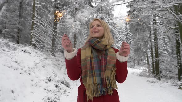 blonde in a red coat with sparkler in a snowy forest