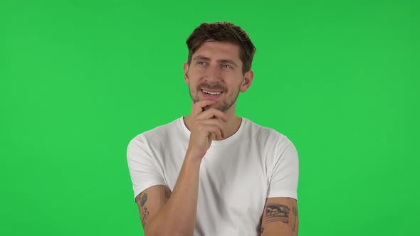 Portrait of Confident Guy Is Daydreaming and Smiling Looking Up. Green Screen