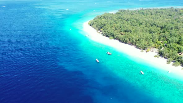 Beautiful tropical island with lush vegetation and white sandy beach, tourists coming by boats on sh