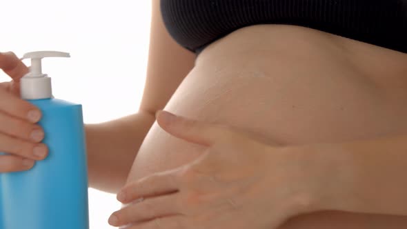 Pregnant Woman Lubricates Her Belly with Nourishing Skin Cream