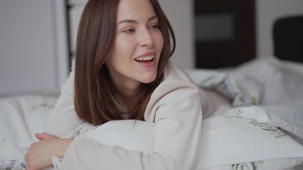 Delighted Female Hugging Pillow on Bed