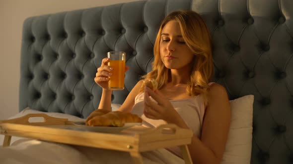 Woman Drinking Orange Juice, Eating Tasty Croissant in Bed, Healthy Breakfast