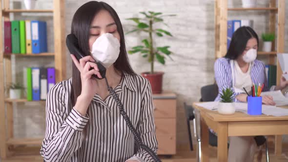 Two Young Asian Girls Office Workers in Protective Medical Masks on Their Faces