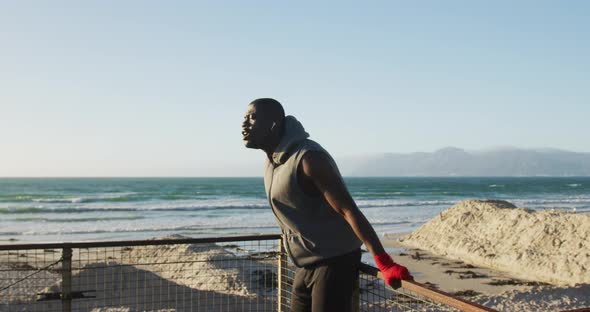 Focused african american man taking break in exercise outdoors by the sea