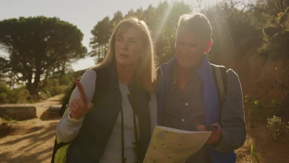 Active senior couple looking map in forest