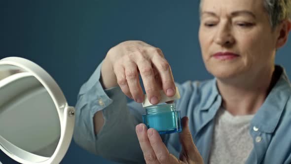 An Elderly Woman Applies an Antiaging Moisturizer