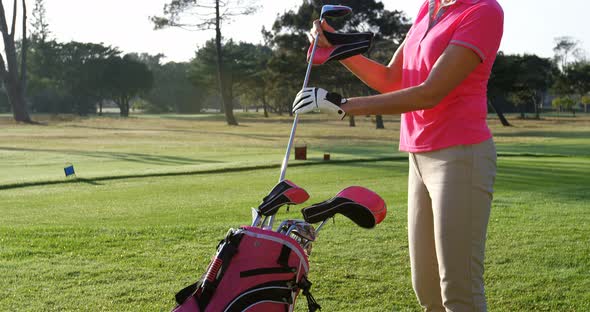 Female golfer removing golf club from golf bag