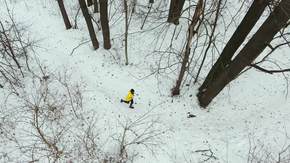 Runner in Yellow Coat Jogging in Winter Forest