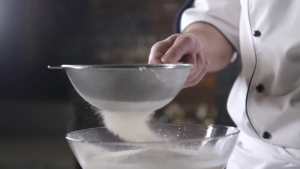 Men's hands sift flour through baking sieve.