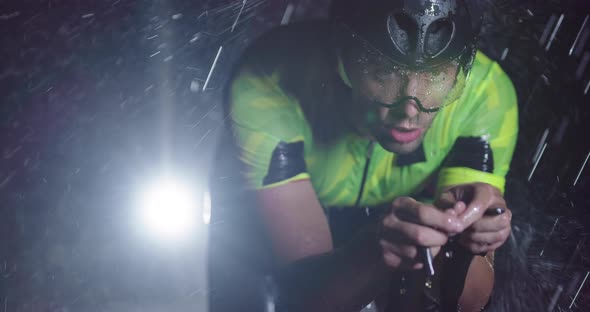 Triathlon Athlete Riding a Professional Racing Bicycle on an Intense Workout in Dark with Rain