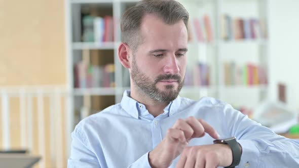 Portrait of Serious Young Man Using Smart Watch