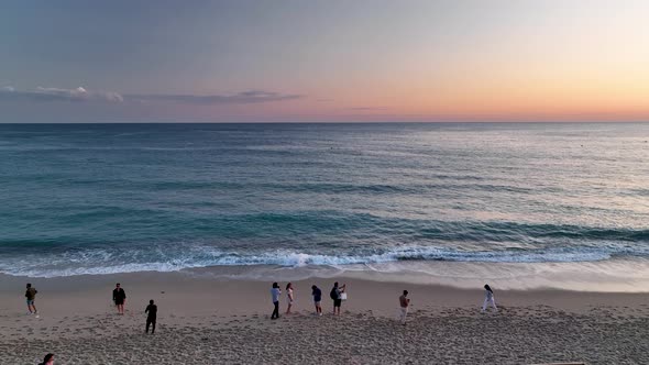 People sit on the beach and watch the sunset