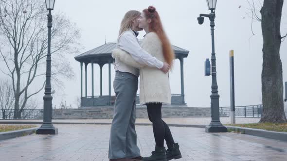 Side View of Happy Young Caucasian Couple Hugging at the Background of Summer House