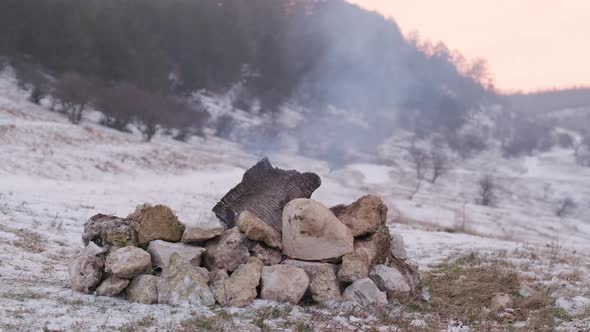 Close Up of a Flame That Goes Out on the Snow Near the Mountain Stream