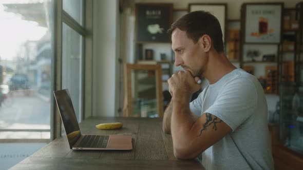 Digital Nomad Works on a Laptop in a Coffee Shop