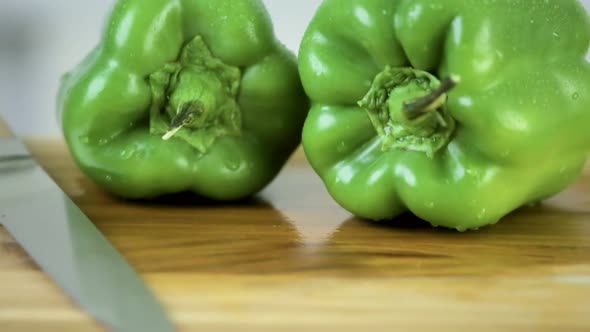 Slicing green bell pepper on a wood cutting board.