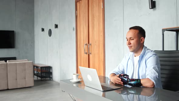 Smiling guy describes black bio hand prothesis and gesticulates talking at online video appointment