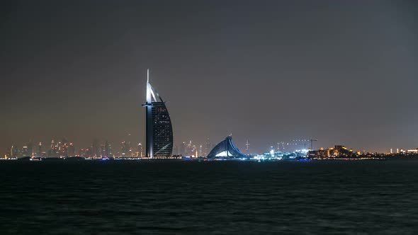 Skyline of Dubai at Night Timelapse with Burj Al Arab in Foreground in Dubai United Arab Emirates