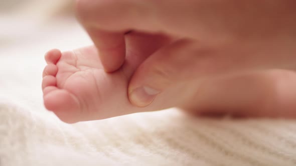 Mother Massaging and Tickling Small Baby Feet. Close Up Slow Motion Shot