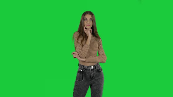 Slender Girl with Long Hair Is Daydreaming and Smiling Looking Up on a Green Screen