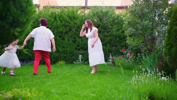 Mom Grandmother and Daughter Have Fun and Play on the Lawn in the Backyard