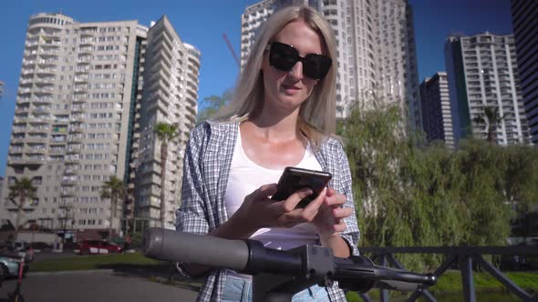 Woman unlocks electric scooter app with her smartphone.