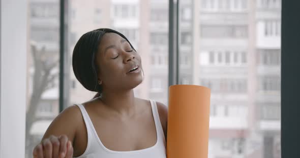 Exhausted Black Woman Holding a Fitness Mat
