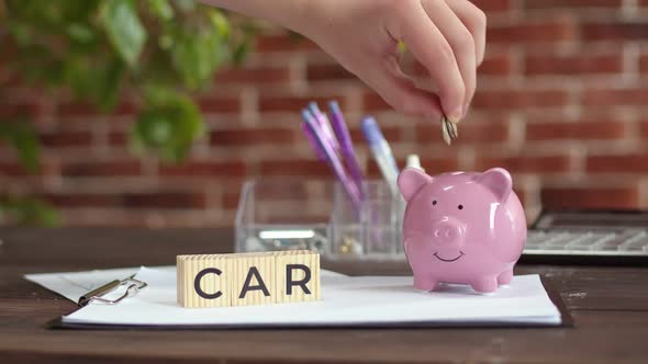 On the Desktop Where There are Wooden Cubes with Inscription Car Person's Hand Puts Coins in Piggy