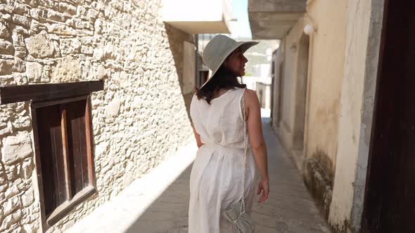 Back View Young Woman in White Dress Walking on Sunny Cyprus Street in Slow Motion