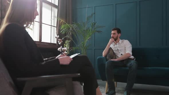 Female Psychologist Listening To the Man Client Sitting During Psychological Session in the Blue