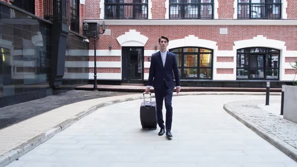 Handsome Young Businessman Going With Luggage From The Airport On City Street