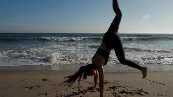 Athletic woman does a handstand on the beach