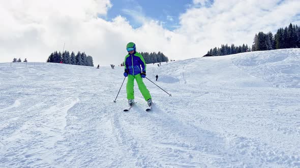 Child Ski Downhill to Camera on Skiing Track at Alpine Resort