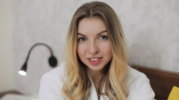 Portrait of Woman Looking at Camera and Smiling While Sitting at the Bed at Home