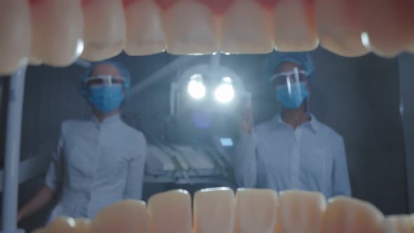 Macro Shot of Patient Opening Mouth and Dentist with Assistant Adjusting Lamp
