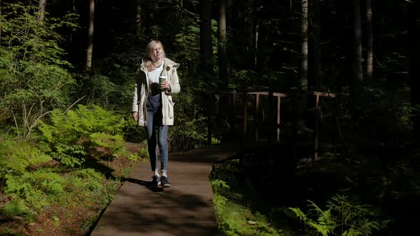 woman walks with a thermomug on a forest trail