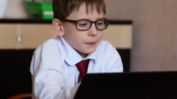 A cute caucasian boy in glasses 7 years old is studying at home doing homework