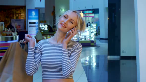 Female Shopper Talks on the Phone at the Mall