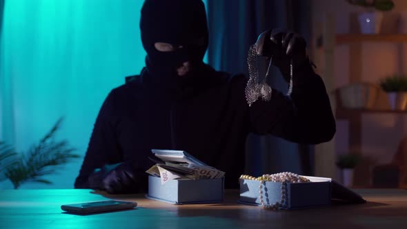 Portrait of a Robber in a Balaclava with Jewelry in His Hands