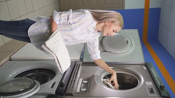 Woman in a Public Laundry Loading Laundry a Public Selfservice Place