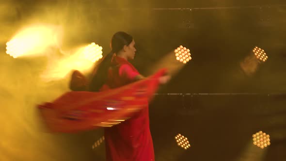A Young Girl Dancer in a Red Sari. Indian Folk Dance. Shot in a Dark Studio with Smoke and Yellow