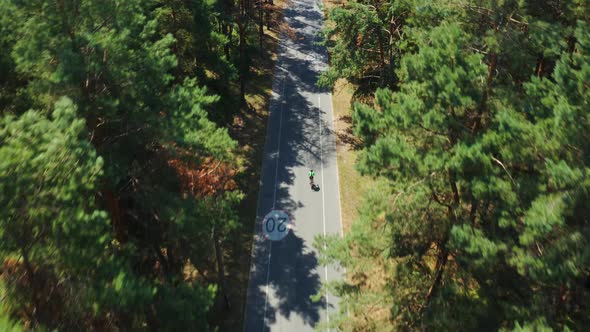 Aerial Tracking Shot of Cyclist Riding Bicycle on Forest Road