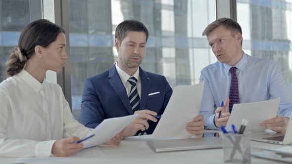 Middle Aged Businessman Reading Documents for His Assistants on Office Table