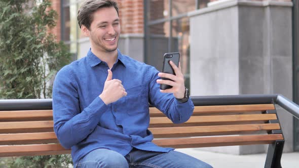 Video Chat on Smartphone by Young Man Sitting Outdoor