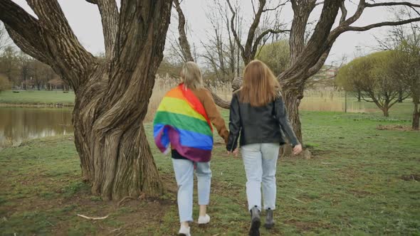 LGBT Couple Wears Rainbow Flag and Runs Around Tree in Park