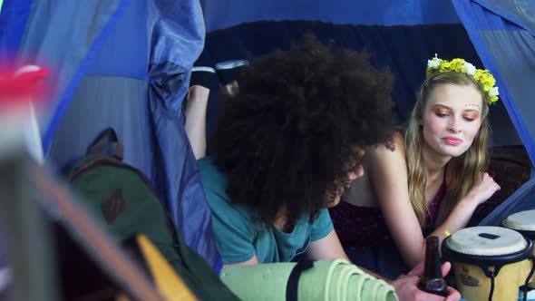 Couple lying on tent and having bottle of beer