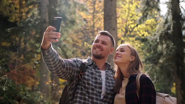 Man and Woman are Taking Selfie By Cellphone at Nature During Hike in Autumn Forest